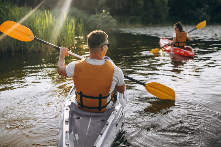 Couple together kayaking down a quiet forest river