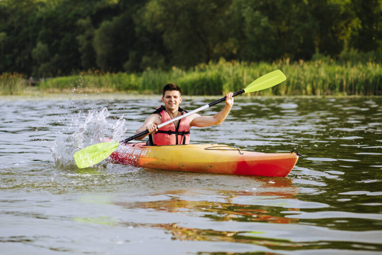 Male kayaker splashing water while active kayaking on high alpine lake