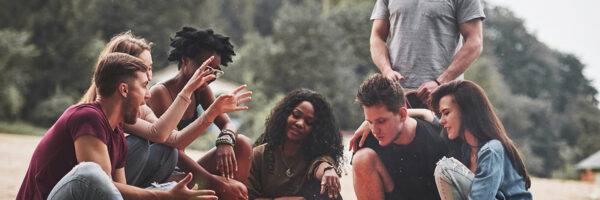 Man talks with interest. Group of people have picnic on the beach. Friends have fun at weekend time.